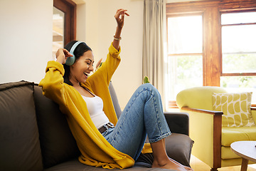 Image showing Woman, music and relax with headphones dancing on living room sofa enjoying good vibes at home. Happy female with smile and dance listening to joyful audio streaming, relaxing on a couch at the house