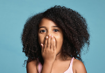 Image showing .Black child, surprised and shocked with wow expression covering mouth in awe feeling positive and excited with natural afro hair. Face portrait of cute kid amazed and happy against blue background.