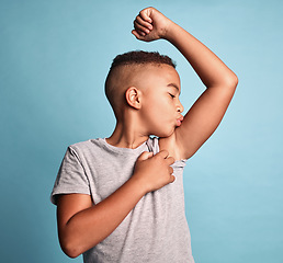 Image showing Children, bicep and kiss with a boy bodybuilder in studio on a blue background for fitness, health or wellness. Sports, strong and kids with a young male child kissing his arm muscle during training