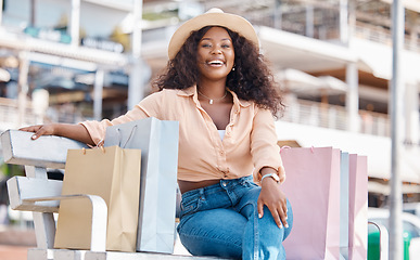 Image showing Black woman, retail shopping bag and outdoor bench break from travel buying, sales and summer market retail fashion promotions in San Francisco California. Happy portrait of wealthy customer spending