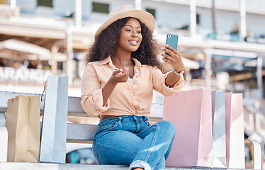 Image showing Retail, shopping and video call with black woman and phone in city for social media influencer, luxury or sales blog. Summer, store and smile with customer on bench to relax with bag, gift or fashion