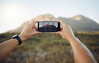 Image showing Hands, phone and mountain picture in nature for adventure, travel and countryside in the outdoors. Hand of traveler taking a photo of the natural environment with mobile smartphone in South Africa