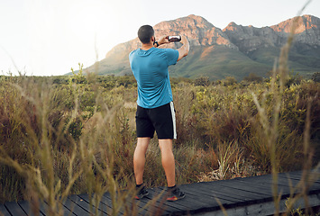 Image showing Phone, nature and fitness with a man taking a photograph while out for a sports run in the wilderness with a view. Exercise, training and workout with a picture of the mountain taken by male athlete