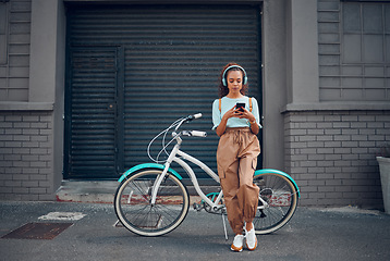 Image showing Headphone, woman and phone with bicycle in city listening to music or podcast streaming outdoor in summer with trendy look. Eco friendly transportation for carbon footprint bike using 5g network