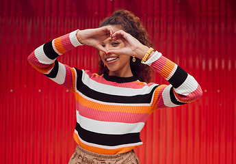 Image showing Heart shape, hands and portrait of a happy woman in a studio with trendy, stylish and fashion clothes. Happiness, smile and love gesture with girl model from Puerto Rico standing by a red background.