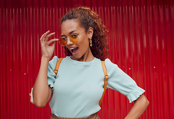 Image showing Trendy, fashion of black woman cool sunglasses with a playful attitude on red background outside. Happy girl model with comic expression and positive energy or attitude on tourism trip in Sao Paulo