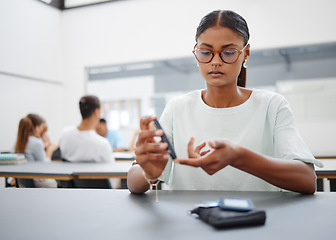 Image showing Diabetes, finger prick and black woman with blood sugar test to check glucose level sitting at desk in class. Sick and diabetic female student using glucometer pen for control and healthcare