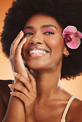 Image showing Flower, model and makeup with afro in closeup for fashion, cosmetic or beauty with orange backdrop. Woman, pink orchid and hair for cosmetics with smile, happy and glow on skin with studio background