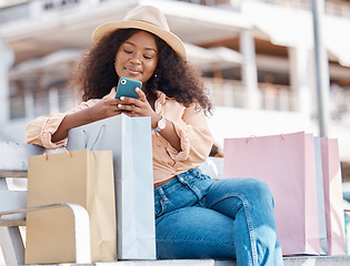 Image showing Phone, shopping and happy black woman with shop and store bags on a bench outdoor. Online, mobile and ecommerce app scroll of a young person smile from Miami with technology and retail paper bag