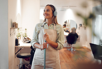 Image showing Small business, woman and cleaning salon as hairdresser, listen to music and headphones with vision, smile and studio. Female entrepreneur, sweeping and in workshop with broom, thinking and happy.