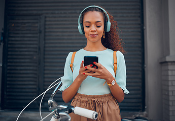 Image showing Music, bicycle and girl on her phone in the city with headphones on. Technology, summer fashion and young woman on her smartphone streaming song, track and radio online and cycling bike in urban town