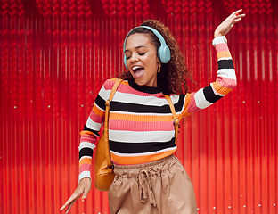 Image showing Dance, music and freedom with a black woman on a red background outdoor for fun or movement. Radio, streaming and audio with a young female dancing while listening to a playlist on headphones