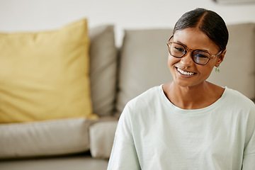 Image showing Home, living room and young Indian woman with smile on face sitting by sofa. Relax, free time and happy girl from India enjoying weekend, holiday and rest in lounge apartment and watching a movie