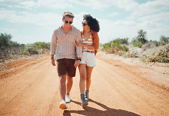 Image showing Couple, sunglasses and walking on dirt road in nature on holiday, vacation or summer safari trip. Diversity, love and man, woman and travel outdoors, talking and bonding or spending time together.