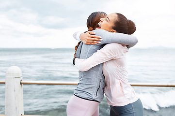 Image showing Fitness, friends and women hug at the ocean, success and workout goals, celebration of teamwork with personal trainer. Health, exercise and training target, happy woman hugging friend at sea waves.