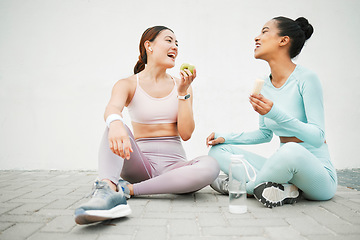 Image showing Fitness women, laughing and eating fruit on training, weight loss exercise and workout break by Canada city wall. Smile, happy and bonding sports people or friends with apple, banana and health food