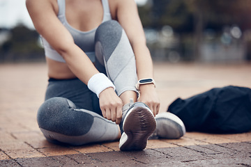 Image showing Workout, fitness and woman tying shoes on feet, sitting on ground before marathon training or running. Health, wellness and sports footwear, motivation for exercise for girl athlete or track runner.