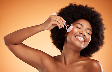 Image showing Beauty, skincare and black woman with jade roller in studio, happy, smile and relax during grooming with mockup background. Face, product and wellness model enjoying facial massage with roller tool