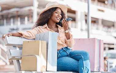 Image showing Shopping, fashion and phone call, a black woman with a smile resting outside a mall. Relax on bench, happy customer after discount sale at shopping mall or designer boutique and talking on smartphone