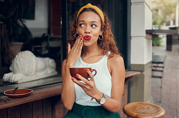 Image showing Coffee, cafe and hand of a black woman with funny face while sitting by a counter at an outdoor restaurant. Coffee shop, quirky and makeup with a playful young female enjoying a drink from a mug
