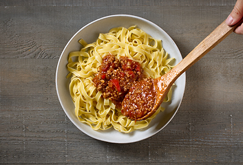 Image showing bologna sauce is added to a bowl of pasta