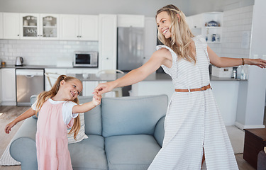 Image showing Family, mother and girl child dancing for fun, energy and love in the living room feeling happy and holding hands to dance at home. Smile of woman and daughter moving to favorite song in USA house