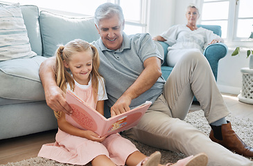 Image showing Book, child and grandfather reading a story for education, knowledge and happiness together on the living room floor of their house. Elderly man helping a girl learn to read in the lounge of home