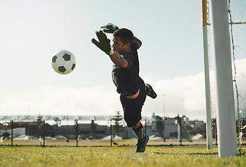 Image showing Soccer, goalkeeper and jump, saving ball from goals at outdoor sports field. Football, goalie and competition game with fitness, goal keeper and soccer ball on grass, success and mission to save goal