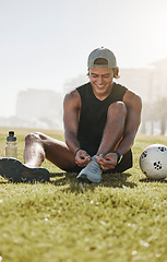 Image showing Fitness, grass and man tie shoes on grass for football training, workout and sports exercise. Summer, energy and health with athlete with sneakers in city park for lifestyle, wellness and soccer ball