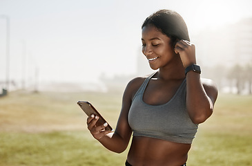 Image showing Black woman, music earphones or phone for fitness podcast, exercise motivation or training radio on sports grass field. Smile, happy and mobile technology for athlete or workout health data on 5g app