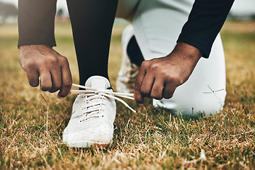 Image showing Baseball, sports and shoes with a man athlete tying his laces on a grass pitch or field for training or a game. Fitness, exercise and footwear with a male player making sure his shoelaces are tied