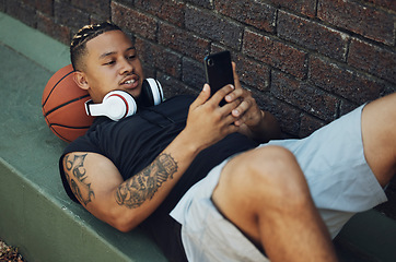 Image showing Basketball player, phone and fitness app on break after sports match, game or practice with ball and black man outdoor. Male fitness athlete with 5g network on social media after sport and exercise