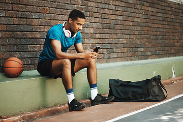 Image showing Man, basketball and phone with sports app, communication and social media online outdoor. Sport male in rest after fitness, exercise and game time check, message or text on mobile 5g smartphone