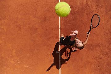 Image showing Top view of a professional female tennis player serves the tennis ball on the court with precision and power