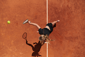 Image showing Top view of a professional female tennis player serves the tennis ball on the court with precision and power