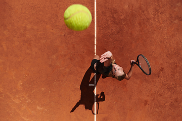 Image showing Top view of a professional female tennis player serves the tennis ball on the court with precision and power