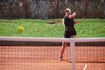 Image showing A young girl showing professional tennis skills in a competitive match on a sunny day, surrounded by the modern aesthetics of a tennis court.