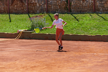 Image showing A young girl showing professional tennis skills in a competitive match on a sunny day, surrounded by the modern aesthetics of a tennis court.