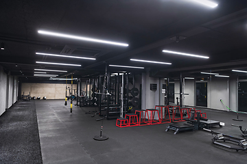 Image showing An empty modern gymnasium with a variety of equipment, offering a spacious, functional, and well-equipped training facility for workouts, fitness, and strength training