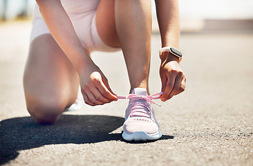 Image showing Fitness, exercise and shoes with a sports woman tying her laces while running on an asphalt road or street. Workout, training and cardio with a female athlete getting ready for a run routine