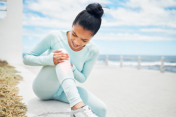 Image showing Fitness, exercise and injury with a sports woman on the beach for a workout, training or to go running. Pain, knee and anatomy with a female athlete suffering with a torn ligament or inflammation