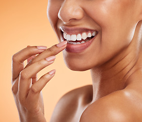Image showing Woman, lips and smile with teeth for cosmetics, makeup and hand for treatment against a studio background. Closeup of female beauty for mouth care, happy smile in satisfaction for oral skincare