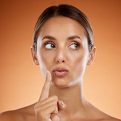 Image showing Woman with sugar scrub on lips, skincare with natural product or handmade wellness treatment in studio. Girl thinking on orange background, exfoliate mouth with peeling smooth skin for beauty idea