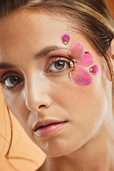 Image showing Woman, flower and beauty eye makeup in portrait for cosmetics, skincare and facial wellness mockup in studio against orange background. Model, cosmetic art and orchid petals design for spring