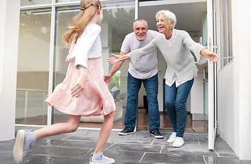 Image showing Grandparents, child and welcome for girl running to hug her grandma and grandpa at front door of home. Excited kid bonding, love and hugging senior man and woman for a family visit in Germany