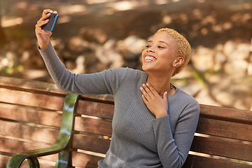 Image showing Park bench, phone selfie and black woman in nature outdoors taking picture. Happy, smile and girl from South Africa with 5g mobile for photo, social media post or comic memory alone at park outside.