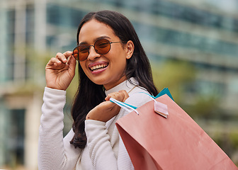 Image showing Shopping bag, retail and portrait of woman with sunglasses walking in city after store sale or discount. Happy, smile and rich posh housewife from Mexico shopping for fashion clothes in urban town.