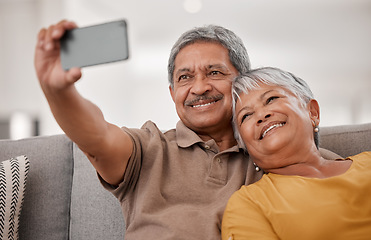 Image showing Phone, selfie and love with a senior couple taking a photograph while sitting on the living room sofa of a home together. Mobile, happy and smile with an elderly male and female psong for a picture