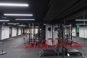 Image showing An empty modern gymnasium with a variety of equipment, offering a spacious, functional, and well-equipped training facility for workouts, fitness, and strength training