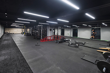 Image showing An empty modern gymnasium with a variety of equipment, offering a spacious, functional, and well-equipped training facility for workouts, fitness, and strength training